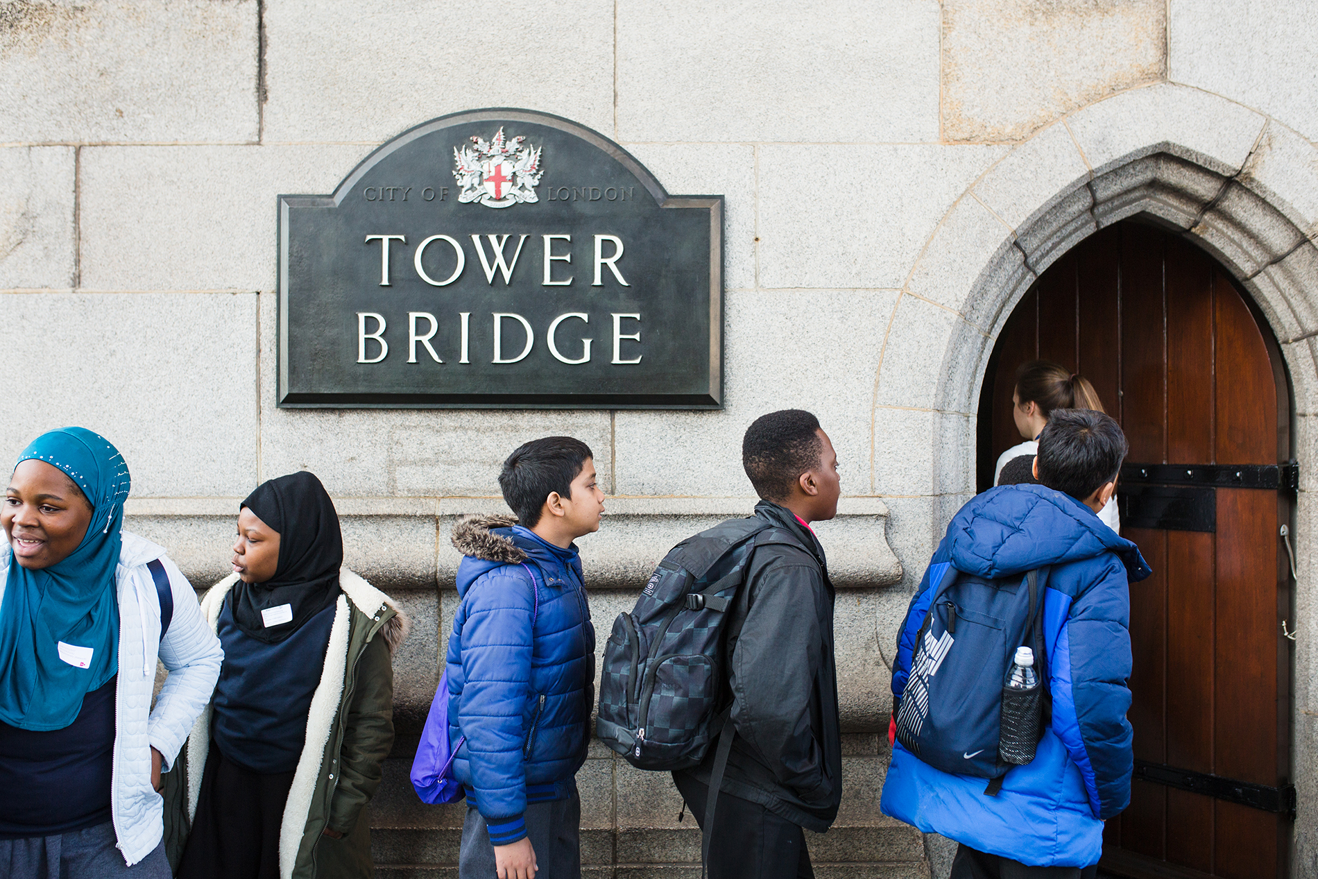 Pupils pass a sign reading Tower Bridge and enter a door